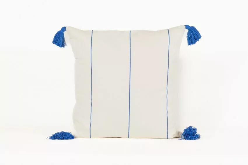 Cojín blanco con líneas azules y borlas en las esquinas