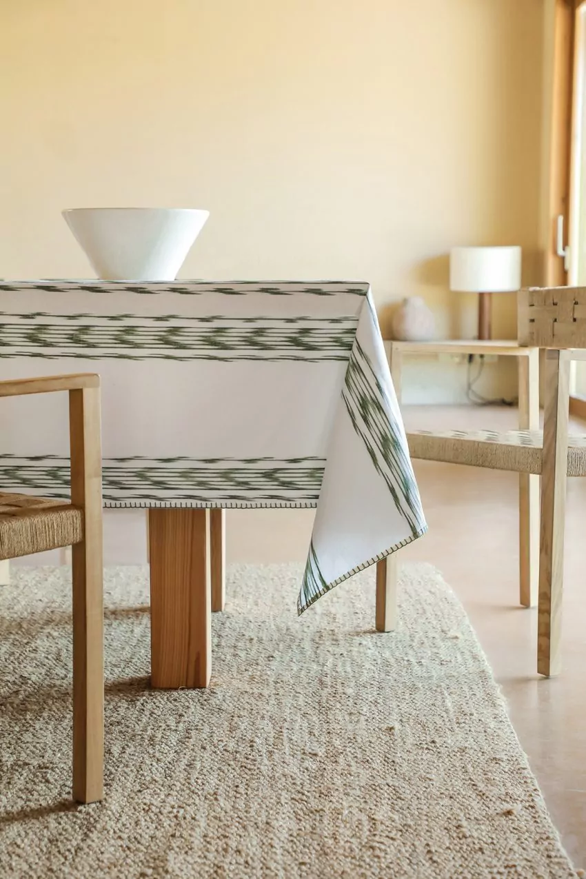 Mantel rectangular blanco con franjas verdes decorativas sobre mesa de madera
